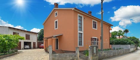 Ein zweistöckiges Haus mit gepflasterter Auffahrt und einem Metallzaun.