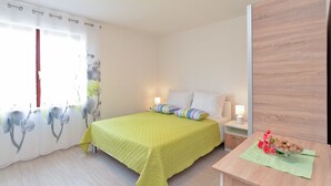 Een slaapkamer met een bed, nachtkastjes, een kledingkast van hout en een raam met gordijnen.