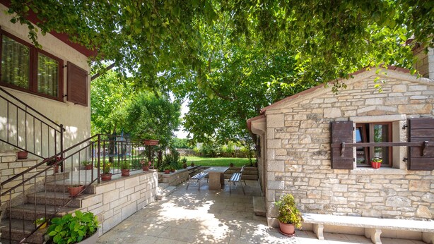 A stone building with a small porch, outdoor seating, and potted plants. - Apartment 1655 (Kanfanar)