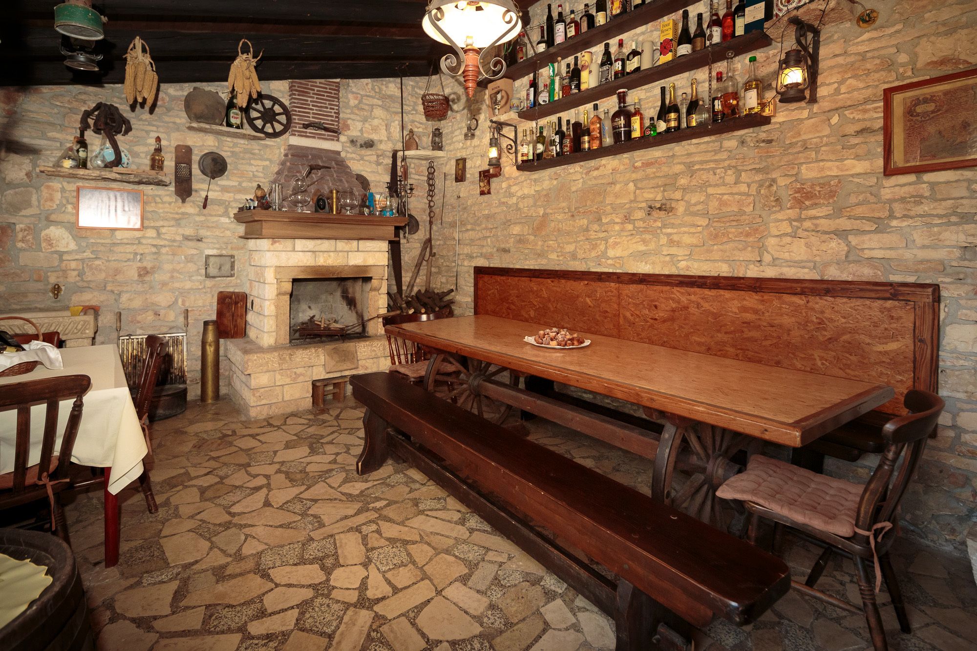 A rustic pub with a stone wall, wooden bench, and a fireplace.