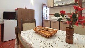 A compact kitchen with a TV, refrigerator, and wooden cabinets. - Apartment 1665 (Vodnjan)