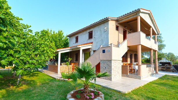 A two-story house with a patio, a small garden, and a stone fireplace. - Apartment 1665 (Vodnjan)