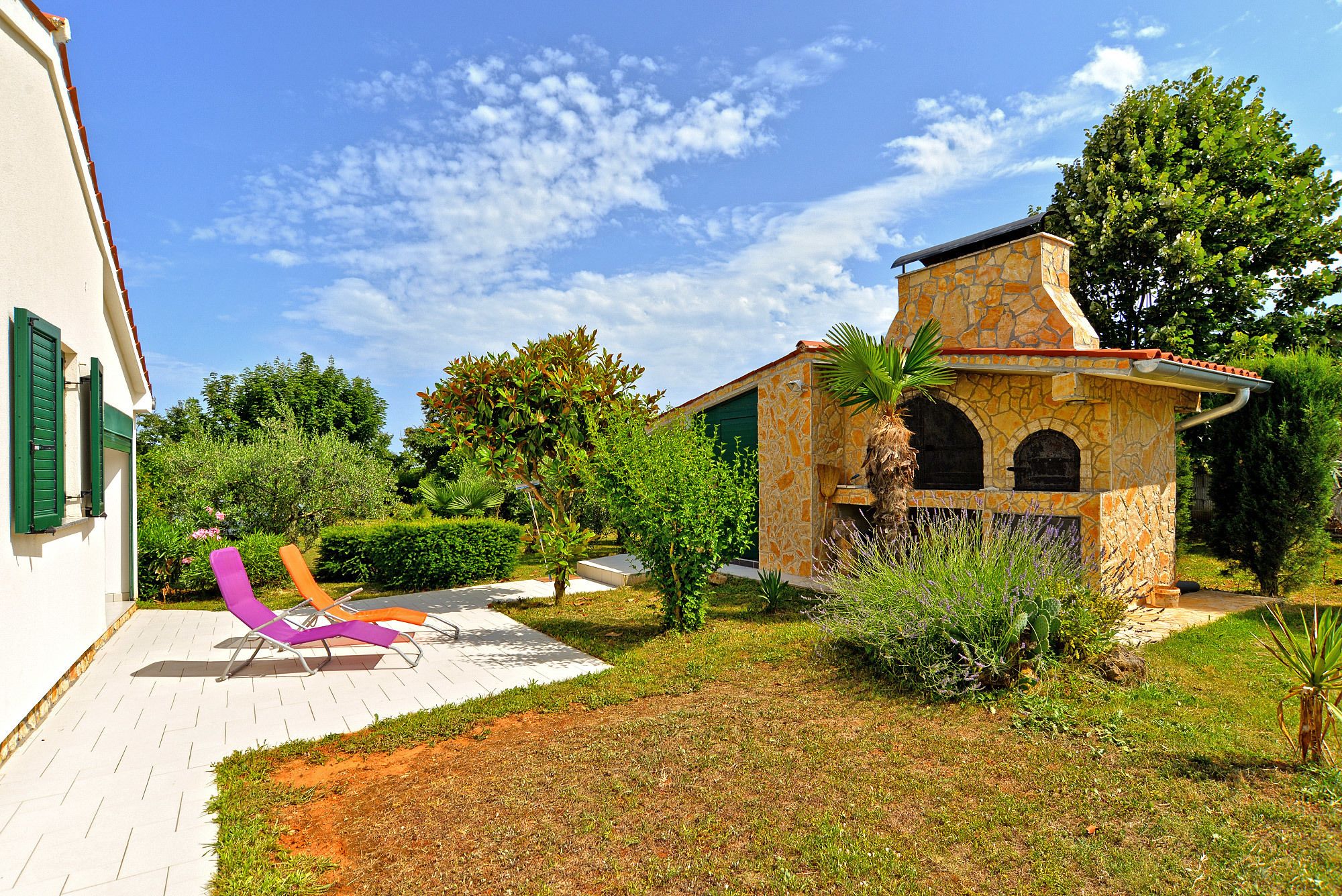 A stone building with a tiled patio and a purple lounge chair.