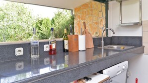 A kitchen with a stone backsplash, a built-in sink, and various kitchen items on the counter. - House 1666 (Liznjan)
