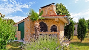 A stone building with a green door, arched windows, and a small roof. - House 1666 (Liznjan)