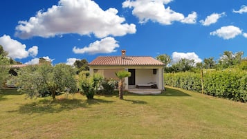 A small house with a tiled roof, a porch, and a well-maintained lawn.