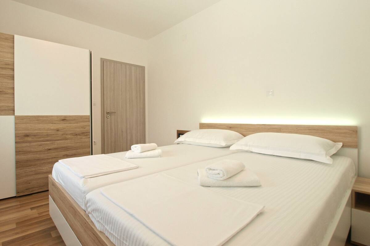 Quarto de hotel moderno com uma cama grande, cabeceira de madeira e um guarda-roupa.