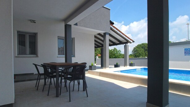 A covered patio area with a pool, a table with chairs, and a view of the pool. - Apartment 1670 (Fazana)