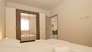 A hotel room with a bed, a wardrobe, a mirror, and a bathroom visible through an open door. - Apartment 1670 (Fazana)