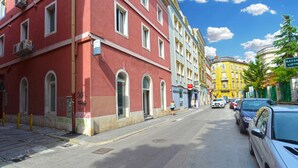 Une vue de rue avec un bâtiment rouge sur la gauche, un bâtiment jaune au centre et un bâtiment vert sur la droite.