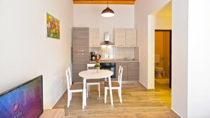 A modern kitchen with wooden cabinets, a round dining table, and white chairs. - Apartment 1674 (Pula)