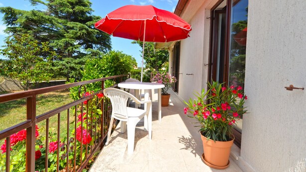 A balcony with a table and chairs, a red umbrella, and potted plants. - Apartment 1674 (Pula)