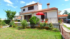 A two-story house with a balcony, a red umbrella, and a garden. - Apartment 1674 (Pula)