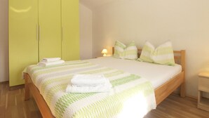 A bedroom with a bed, green wardrobe, and a bedside table with a lamp.