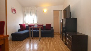 A compact living space with a sofa, a small table, a television, and a cabinet.