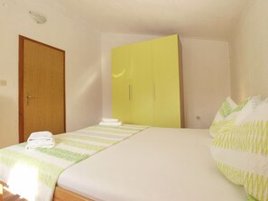 A bedroom with a bed, a green wardrobe, and a wooden door. - Apartment 1680 (Pula)