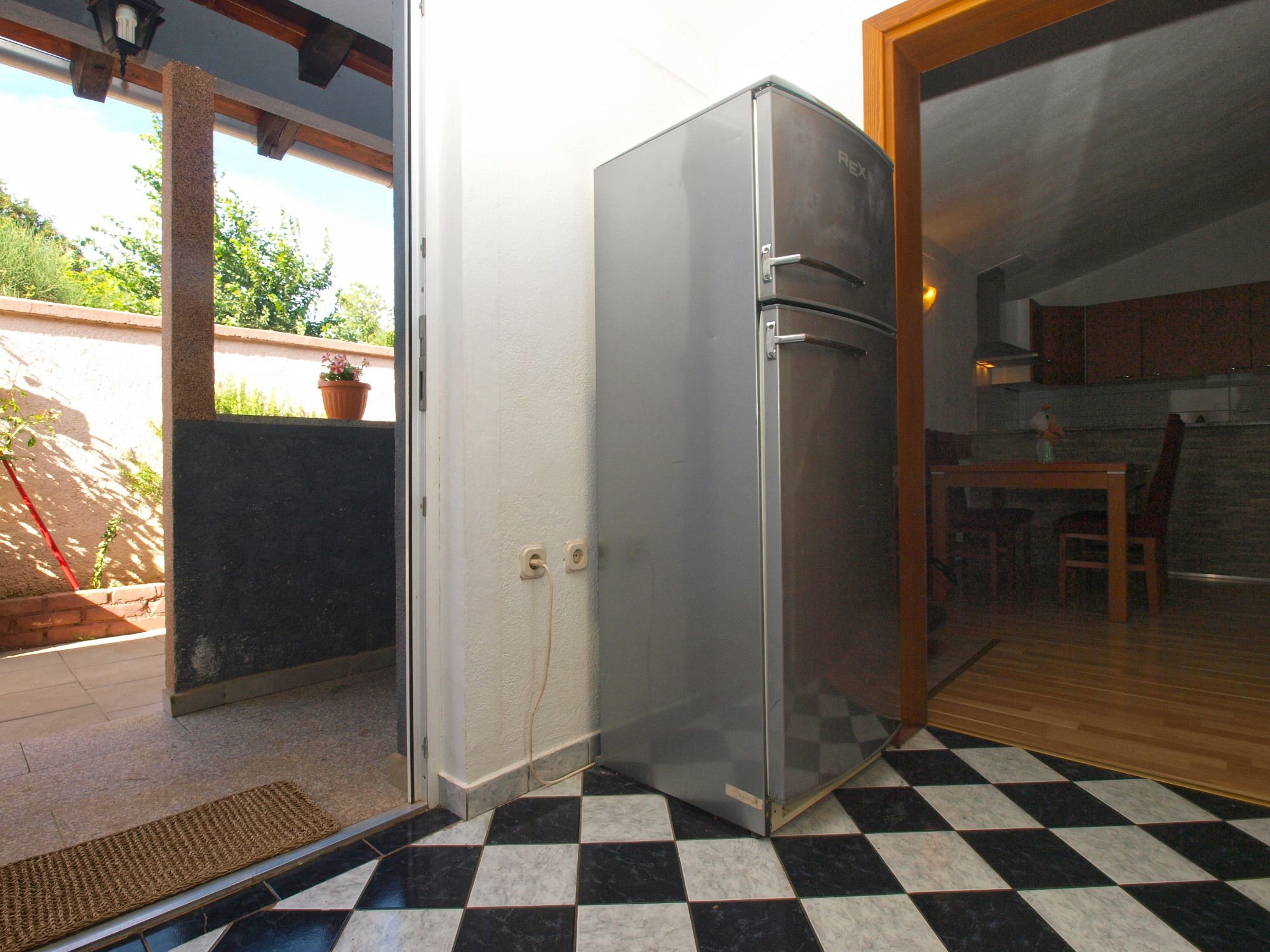 A kitchen with a refrigerator, a dining table, and a chair.