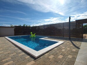 A rectangular swimming pool with a tiled edge, surrounded by a brick patio. - Apartment 1680 (Pula)