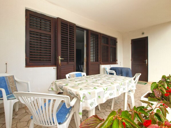 Enjoy dining al fresco on this patio with a table set amidst lush greenery and vibrant flowers.