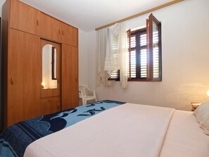 Relax in this serene bedroom with a large bed, a spacious wardrobe, and a window with curtains.