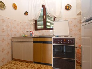 Kitchen features a stainless steel oven, refrigerator, and dishwasher, along with a decorative backsplash and patterned tile flooring.
