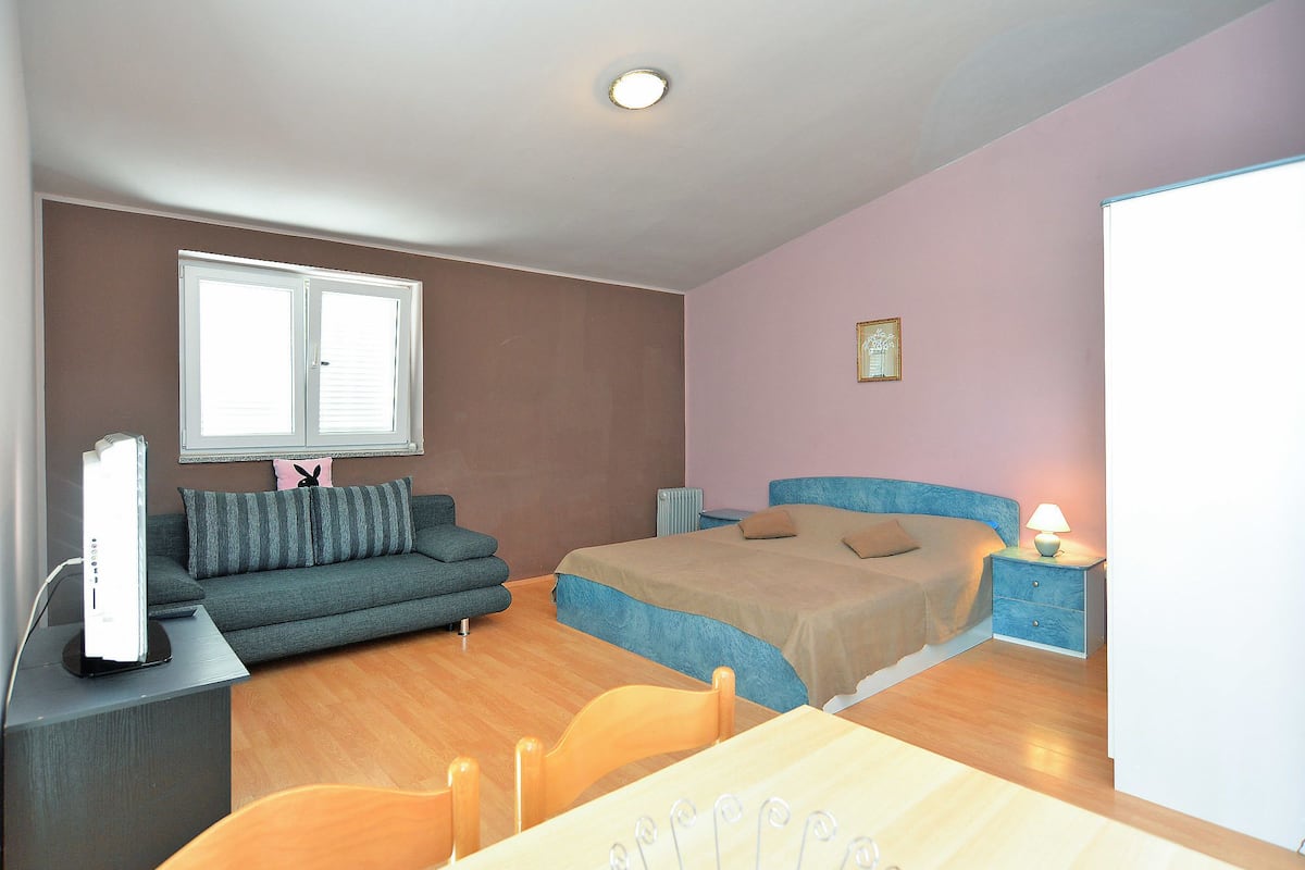 A bedroom with a bed, a sofa, a table, and a chair.