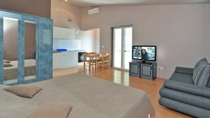Een moderne woonkamer met een bank, een televisie en een eethoek met stoelen en een tafel.