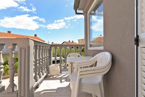 A balcony with white plastic chairs and a table, a window, and a view of houses with red roofs. - Apartment 1692 (Fazana)