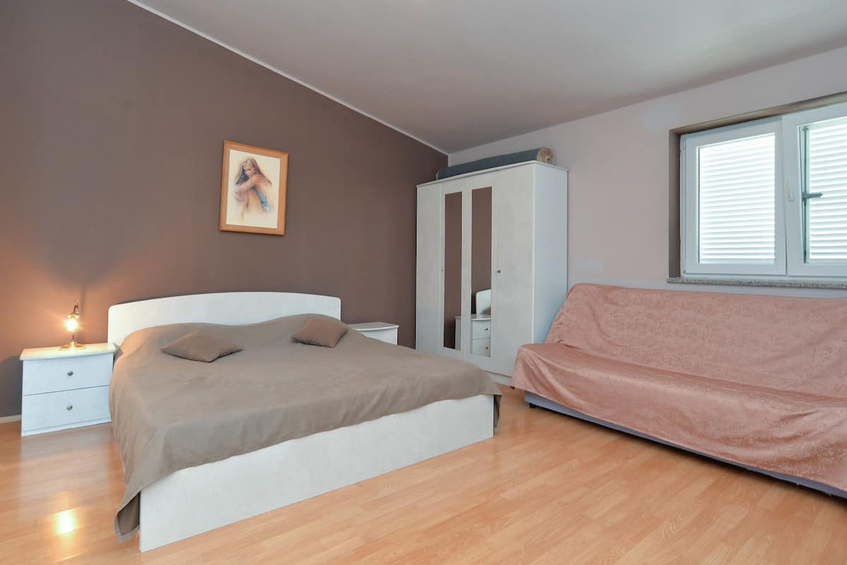A bedroom with a bed, a nightstand, a wardrobe, and a window.