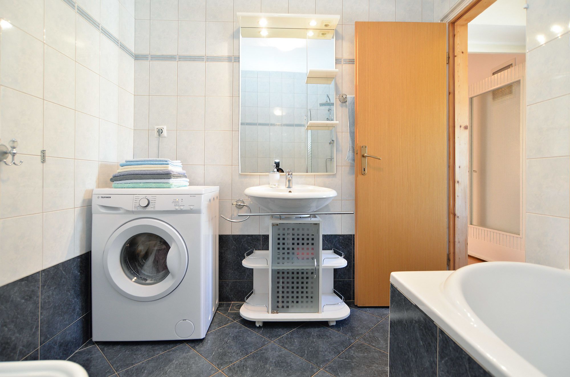 Une salle de bain moderne équipée d’un lave-linge, d’un évier et d’une baignoire.
