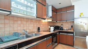 Een moderne keuken met houten kastjes, een roestvrijstalen koelkast, een magnetron en een vaatwasser.