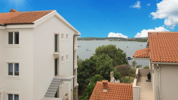 A coastal building with a red-tiled roof, white walls, and a view of the sea with boats. - Apartment 1704 (Medulin)