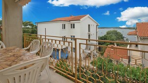 A balcony with a table and chairs, overlooking a body of water and buildings. - Apartment 1704 (Medulin)