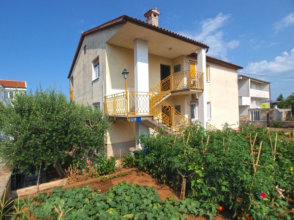 Un immeuble de deux étages doté d’un balcon et d’un jardin à l’avant.