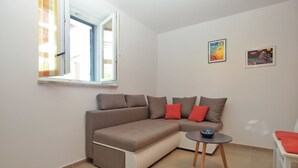 A modern living room with a sectional sofa, a small table, and two framed artworks on the wall. - House 1708 (Barban)