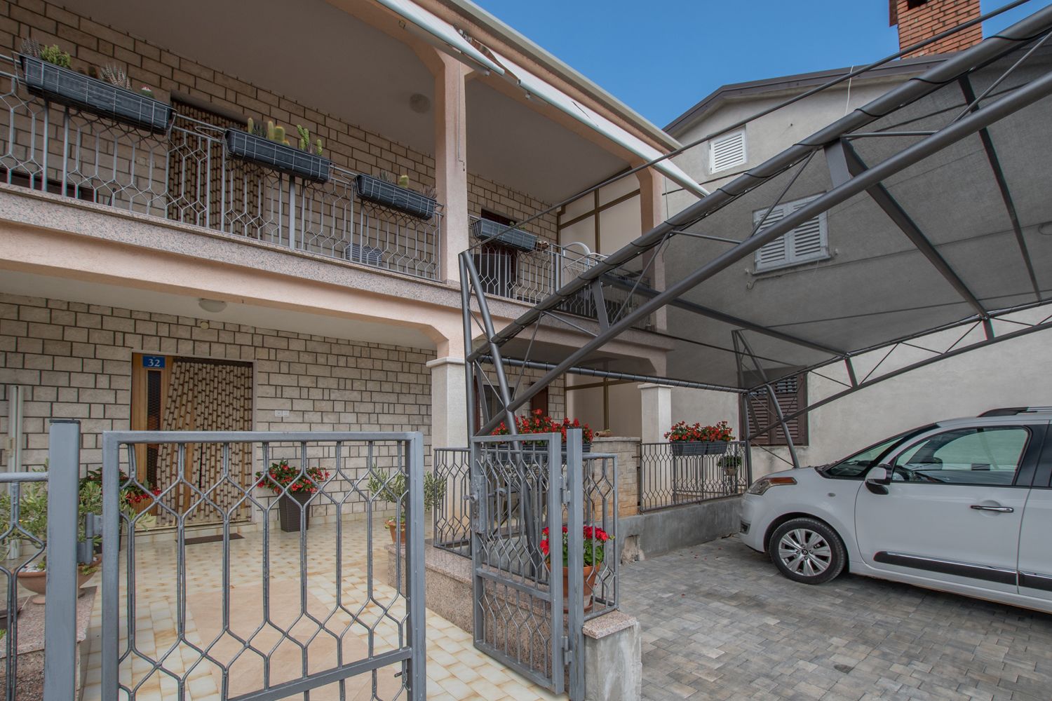 A two-story building with a covered parking area and a car parked inside.