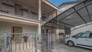 A two-story building with a covered parking area and a car parked inside.