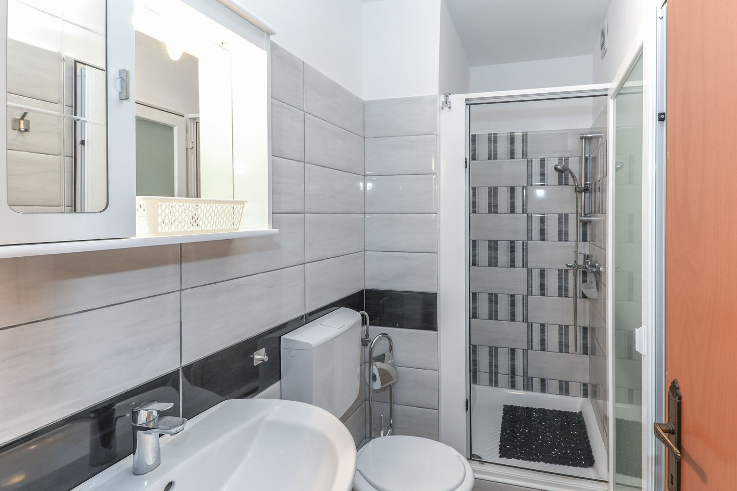 Een moderne badkamer met toilet, wastafel en douche.