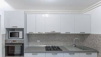 A modern kitchen with white cabinets, a microwave, an oven, a gas stove, and a sink.