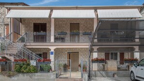 A two-story building with a brick facade, a metal staircase, and balconies with potted plants. - Apartment 1709 (Umag)