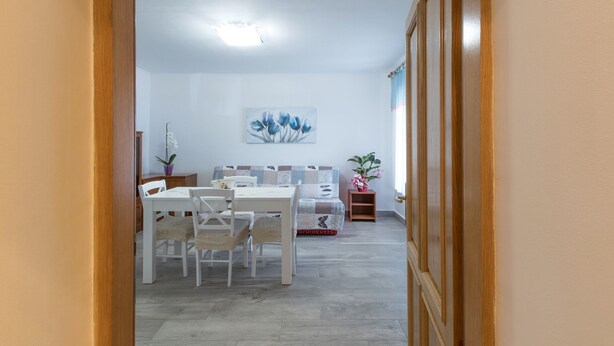 A dining area with a white table and chairs, a ceiling light, and a painting on the wall. - Apartment 1709 (Umag)