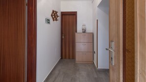 A hallway with wooden doors, a cabinet with drawers, and a wall-mounted light fixture. - Apartment 1709 (Umag)