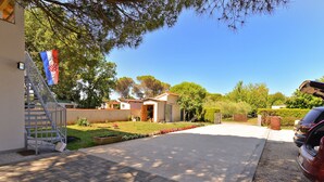 A residential driveway leading to a house with a small garden and a flag. - Apartment 1713 (Fazana)