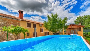 A swimming pool with a stone wall and a wooden deck. - House 1735 (Vodnjan)