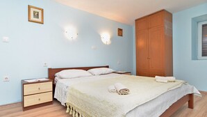 A bedroom with a bed, wooden wardrobe, bedside tables, and wall-mounted lights. - House 1736 (Medulin)