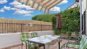 A patio with a table and chairs, a covered area, and a bamboo fence. - House 1736 (Medulin)