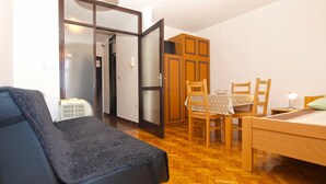 Una habitación con una cama, una mesa de comedor con sillas, un sofá y un armario.