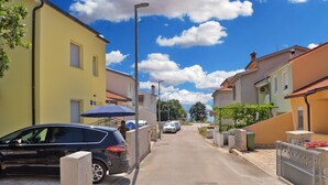 A narrow street lined with colorful buildings, a parked car, and a stop sign. - Apartment 1739 (Medulin)