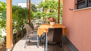 Un patio techado con suelo de baldosas, una mesa con sillas y una planta en maceta.