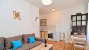 Una sala de estar moderna con un sofá, una mesa de comedor y una cocina con armarios y un refrigerador.